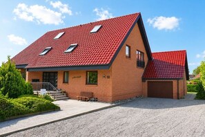 A two-story house with a red-tiled roof, a brick facade, and a gravel driveway. - Holiday apartment with 1 bedroom (Kellenhusen)