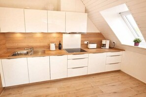 A modern kitchen with white cabinets, a wooden countertop, and a skylight. - Holiday apartment with 1 bedroom (Kellenhusen)