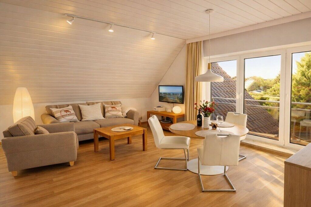 A modern living room with a sofa, coffee table, and chairs, a television, and a large window with a view.