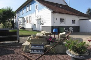 A building with a sign that reads 'TERIENHAUS BREUERS' in front of a blue and white house. - |---former stable---| (Langelsheim)