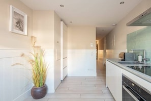 A modern kitchen with a central island, a built-in oven, and a backsplash. - Seehaus Allensbach “Ocean Suite” (Allensbach)