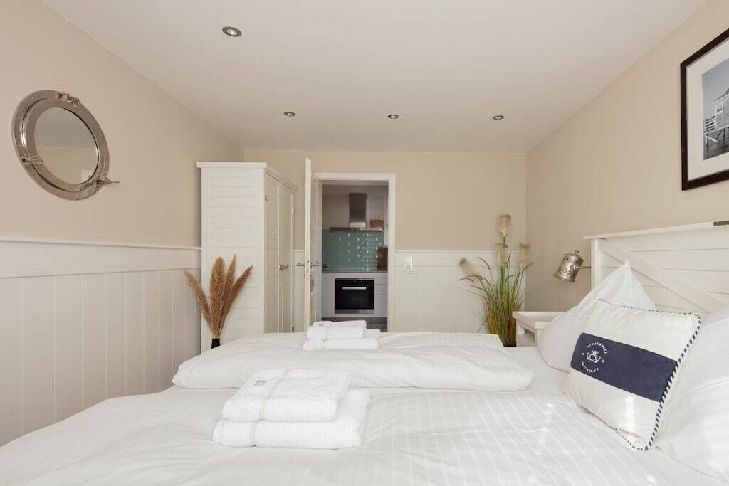A hotel room with a bed, a mirror, a wardrobe, and a bathroom visible through an open door.