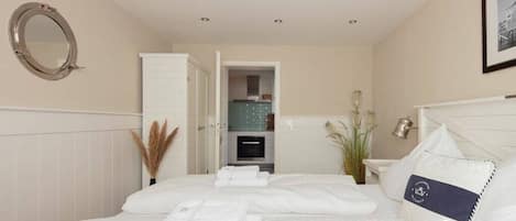 A hotel room with a bed, a mirror, a wardrobe, and a bathroom visible through an open door.