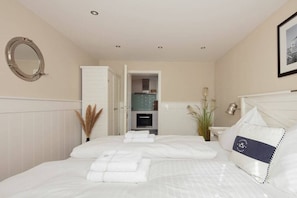 A hotel room with a bed, a mirror, a wardrobe, and a bathroom visible through an open door. - Seehaus Allensbach “Ocean Suite” (Allensbach)