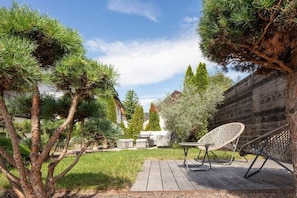 A patio area with a wooden deck, a white wicker chair, and a small table. - Seehaus Allensbach “Ocean Suite” (Allensbach)