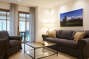 Ein Wohnzimmer mit einer Couch, einem Glastisch und einem Bild an der Wand.