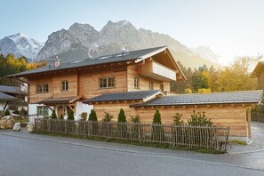 Eine Holzhütte mit Balkon vor einer Bergkulisse.