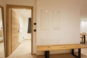 A hotel room with a wooden bench, a door leading to another room, and a wall-mounted radiator. - SCHÖNANGER in the CHALET ZUGSPITZEREI (Grainau)