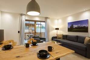 Una sala moderna con una mesa de comedor de madera, un sofá gris y un cuadro de un paisaje montañoso.