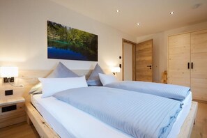 Ein Doppelbett mit Holz Kopfteil, ein Nachttisch mit Lampe und ein großes Gemälde einer Naturlandschaft an der Wand.