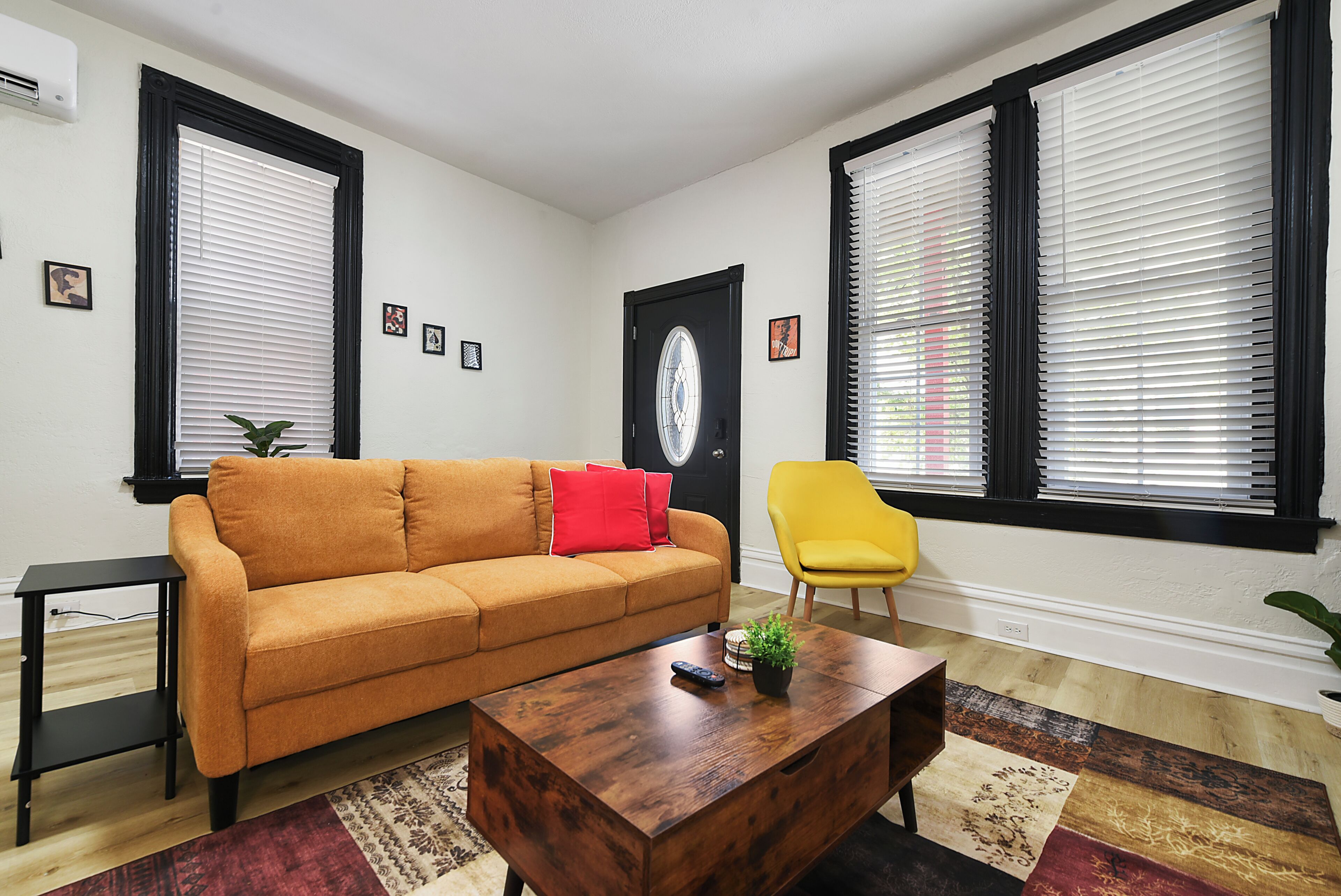 A living room with a sofa, a yellow chair, a coffee table, and a door with a glass window.