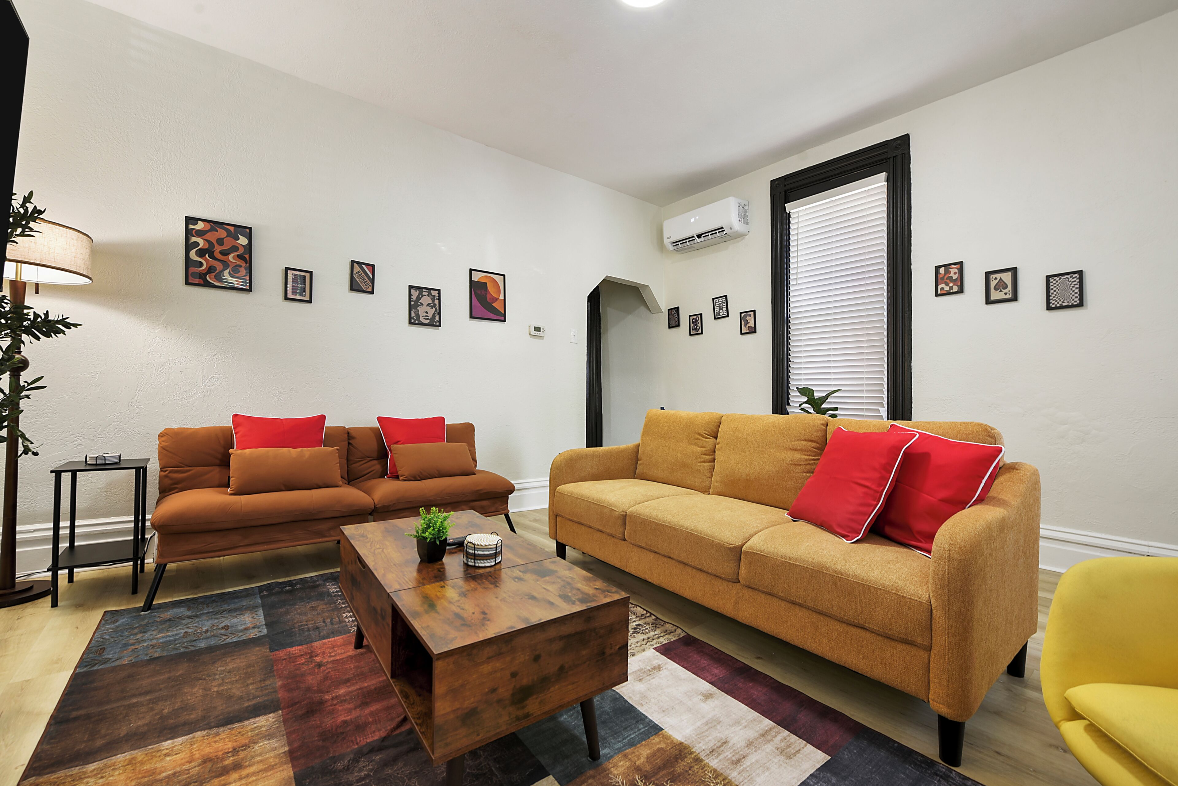 A living room with two sofas, a coffee table, and a yellow armchair.