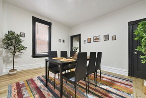 Ein Essbereich mit einem schwarzen Tisch, Stühlen und einem farbenfrohen Teppich.