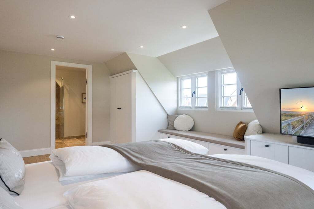 Ein Schlafzimmer mit einem Bett, einem Fernseher, einem Fenster und einer Treppe.