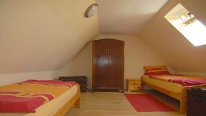 Um quarto de sótão pequeno e acolhedor, com duas camas, um guarda-roupa e um claraboia.
