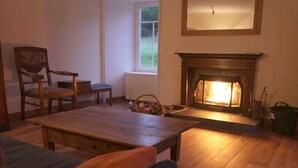 Quarto aconchegante com lareira, uma mesa de madeira e uma cadeira.