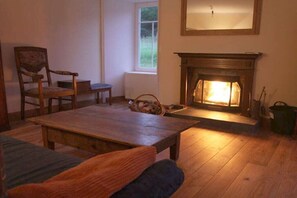 A cozy room with a fireplace, a wooden table, and a chair. - Holiday home with 3 bedrooms (Dufftown \/ Glennrinnes)