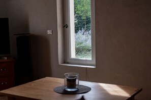 Une pièce avec une fenêtre, une table et une petite lampe de chevet.
