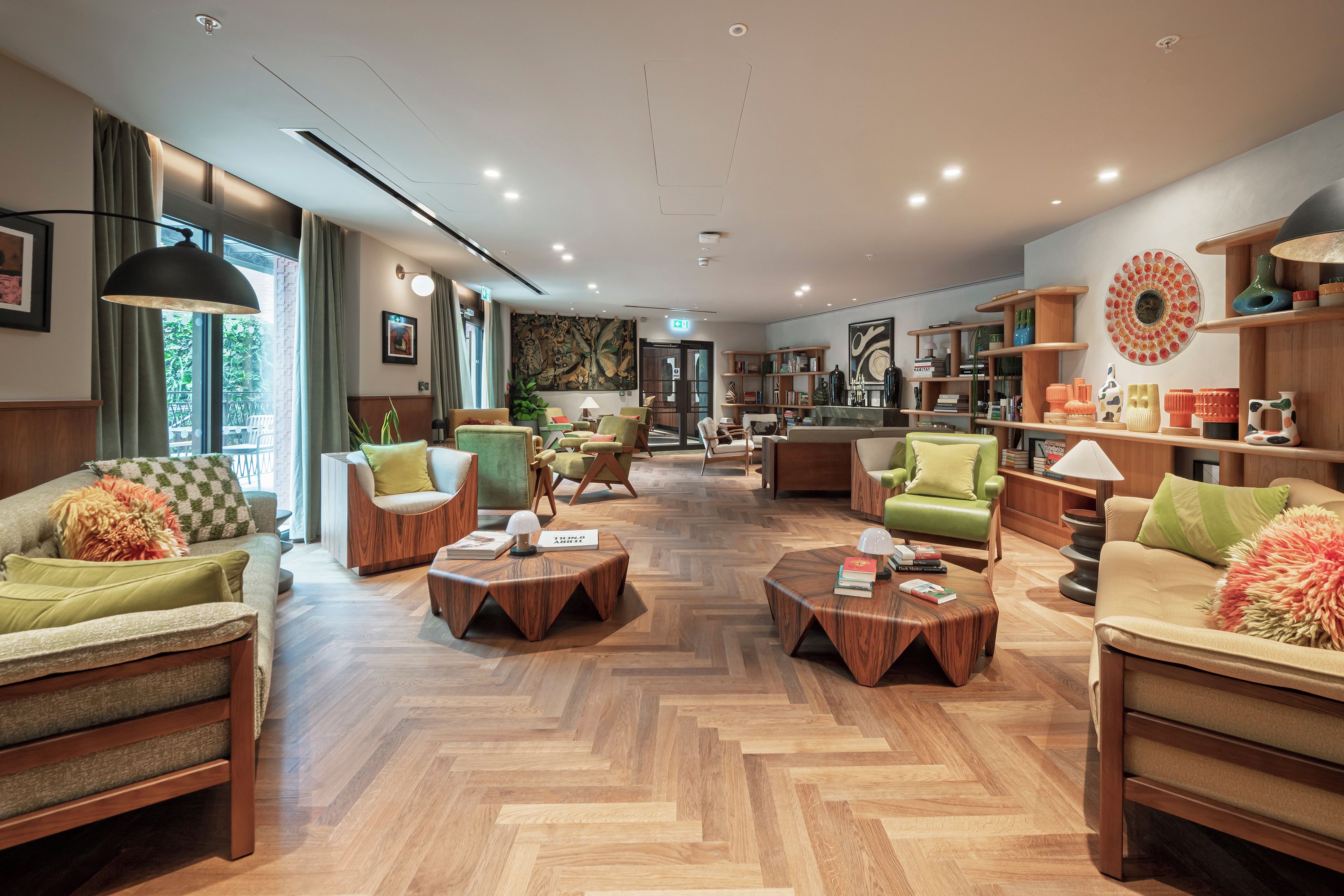 Amplia sala de estar con diversas opciones de asientos, una mesa de centro y una estantería llena de libros y objetos decorativos.