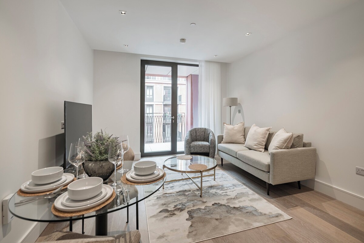 A modern living room with a sofa, a glass coffee table, and a dining area with plates and glasses.