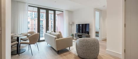 Un salon moderne comprenant un canapé, des fauteuils, une table à manger et un téléviseur.