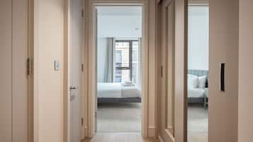 Un couloir d’hôtel menant à une chambre avec un lit, une fenêtre et une vue sur l’extérieur.