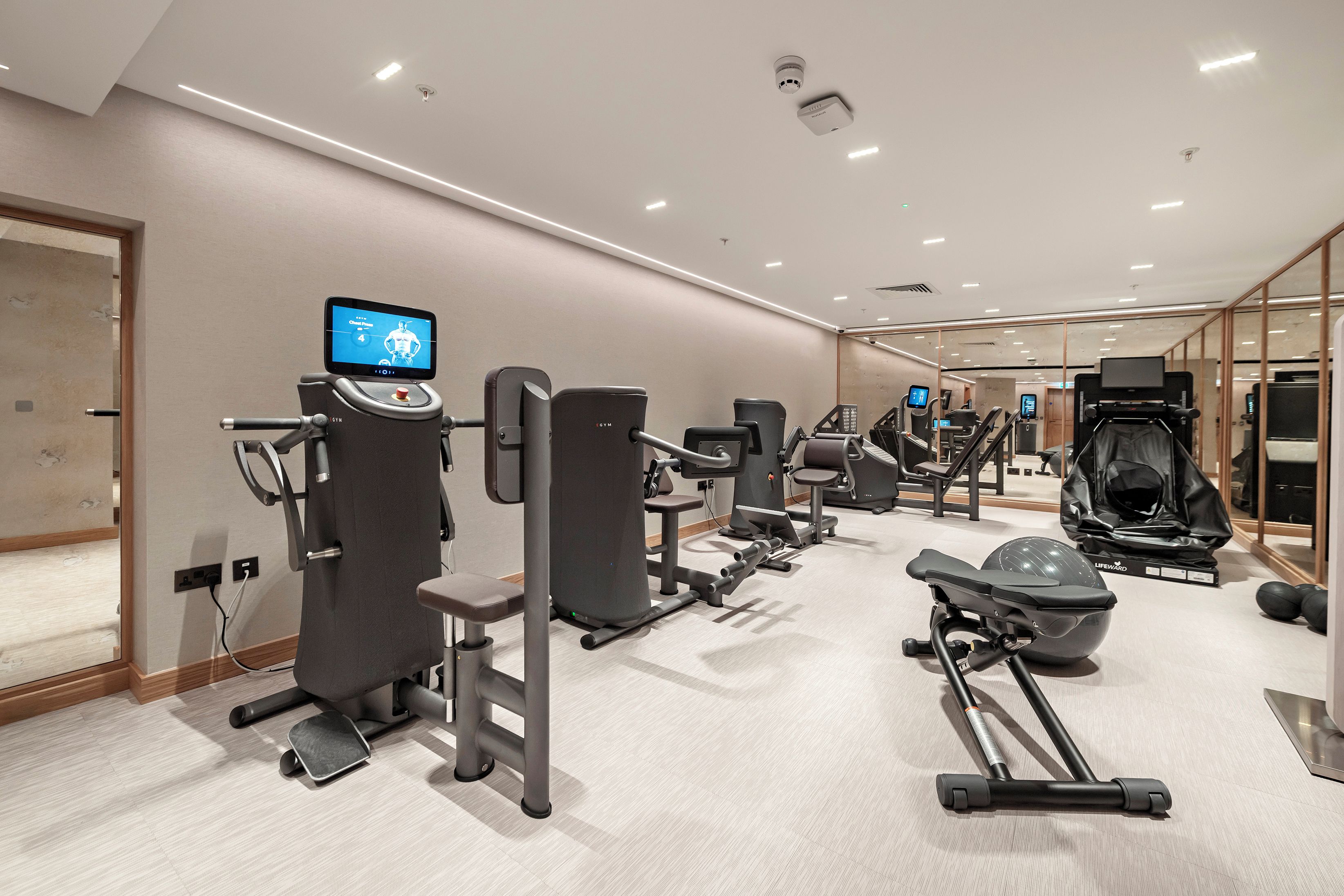 A modern gym with various exercise equipment, including a treadmill, elliptical, and weight machines.