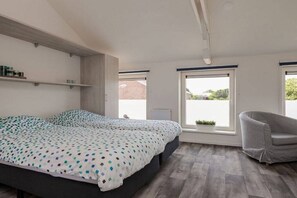 A bedroom with a bed, a chair, and a window. - Willebrordstraat 13 Studio 3 (Westkapelle)