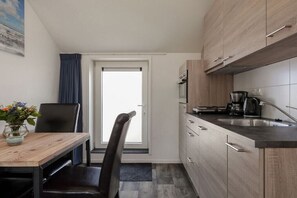 A compact kitchen with wooden cabinets, a coffee maker, and a sink. - Willebrordstraat 13 Studio 3 (Westkapelle)