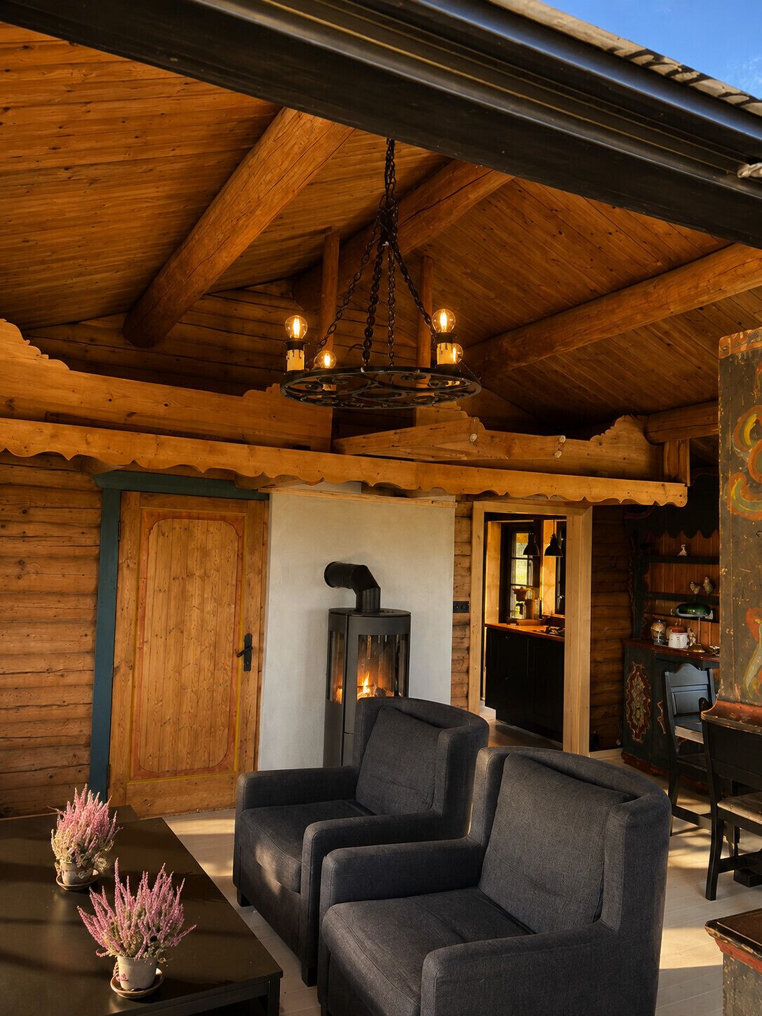 Un intérieur chaleureux avec un plafond en bois, une cheminée et un coin repas comprenant des chaises et une table.