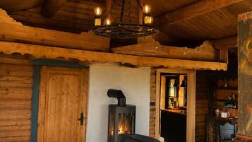 Un intérieur chaleureux avec un plafond en bois, une cheminée et un coin repas comprenant des chaises et une table.