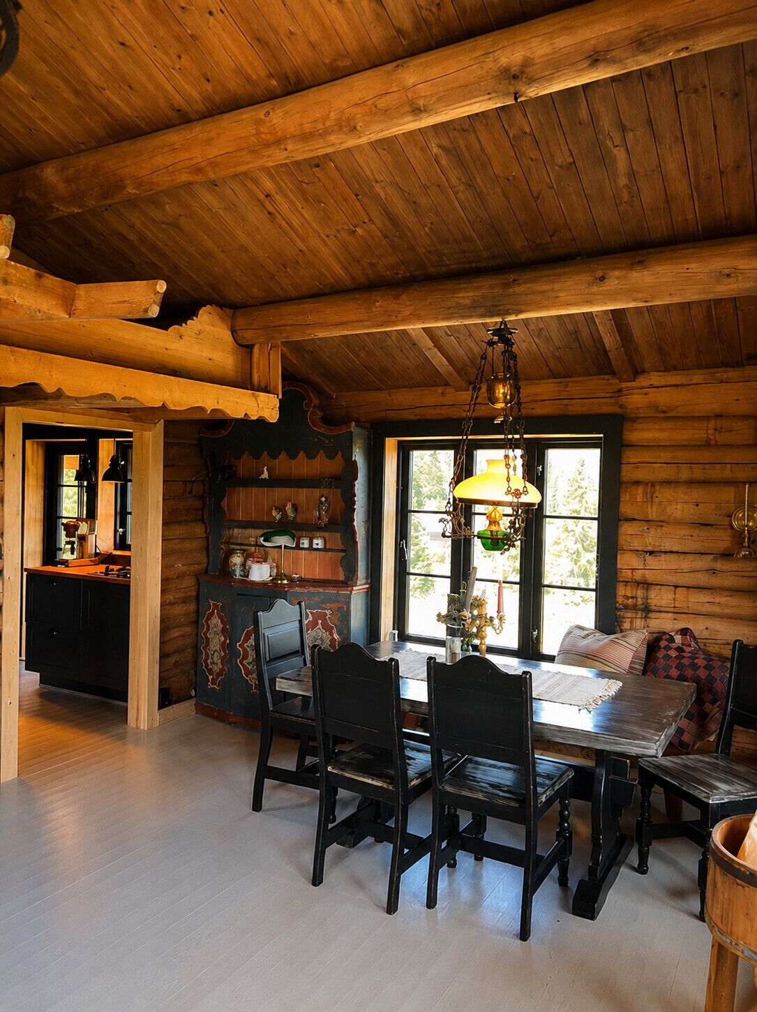 Un intérieur rustique en bois, avec une table à manger, des chaises et un luminaire suspendu.