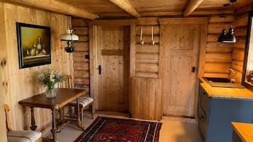A wooden interior with a dining table, bench, and a rug.