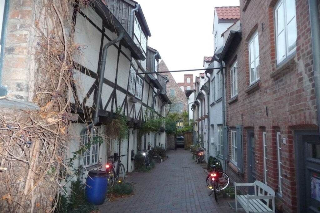 A narrow street with traditional half-timbered buildings, bicycles parked along the sides, and a clear sky.