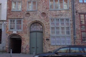 A brick building with a green door, multiple windows, and a car parked in front. - Holiday apartment with 1 bedroom (Lübeck)