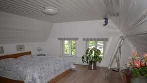 A bedroom with a bed, two windows, a ceiling fan, a potted plant, and a tripod. - Holiday home in Alkersum with swimming pool (Alkersum)