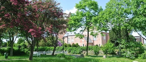 A garden with a pond, trees, and a building with a brick facade.