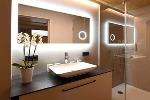 A modern bathroom with a large mirror, a vessel sink, and a glass-enclosed shower. - Holiday apartment in Au with swimming pool (Au)