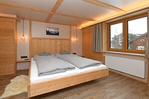 A wooden-framed room with a bed, a window, and a radiator. - Holiday apartment in Au with swimming pool (Au)
