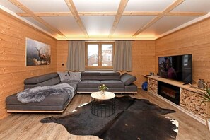 A modern log cabin interior with a sectional sofa, a flat-screen TV, and a fireplace. - Holiday apartment in Au with swimming pool (Au)