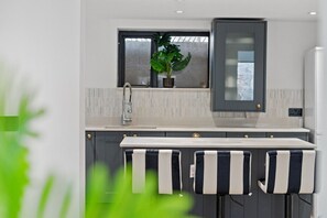 A modern kitchen with a built-in sink, a window above the counter, and a potted plant. - Large 5BR Home in Newport | Ideal for Work Crews | Sleeps 12 (Newport)