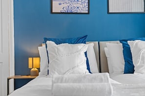 A hotel room with a bed, pillows, a nightstand, a lamp, and a framed picture on the wall. - Large 5BR Home in Newport | Ideal for Work Crews | Sleeps 12 (Newport)