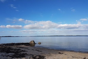 A calm body of water with a sandy beach and scattered rocks. - Holiday apartment with 1 bedroom (Glücksburg)