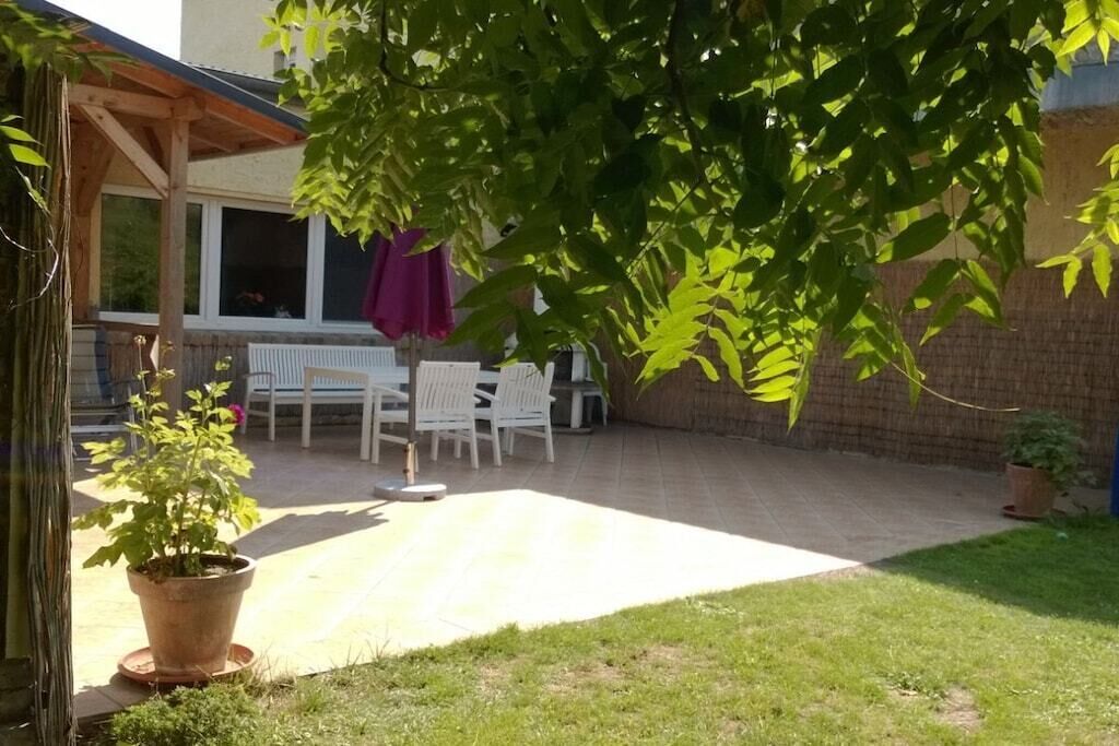Ein überdachter Patio-Bereich mit Tisch und Stühlen, einem Blumentopf und einer Ziegelwand im Hintergrund.