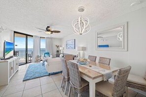 Ein modernes Wohnzimmer mit Balkon, Essbereich und Deckenventilator.