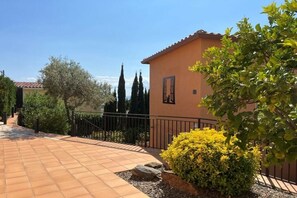 A paved pathway leading to a building with a tiled roof, surrounded by greenery and a metal fence. - Holiday home in Roses with swimming pool (Roses)
