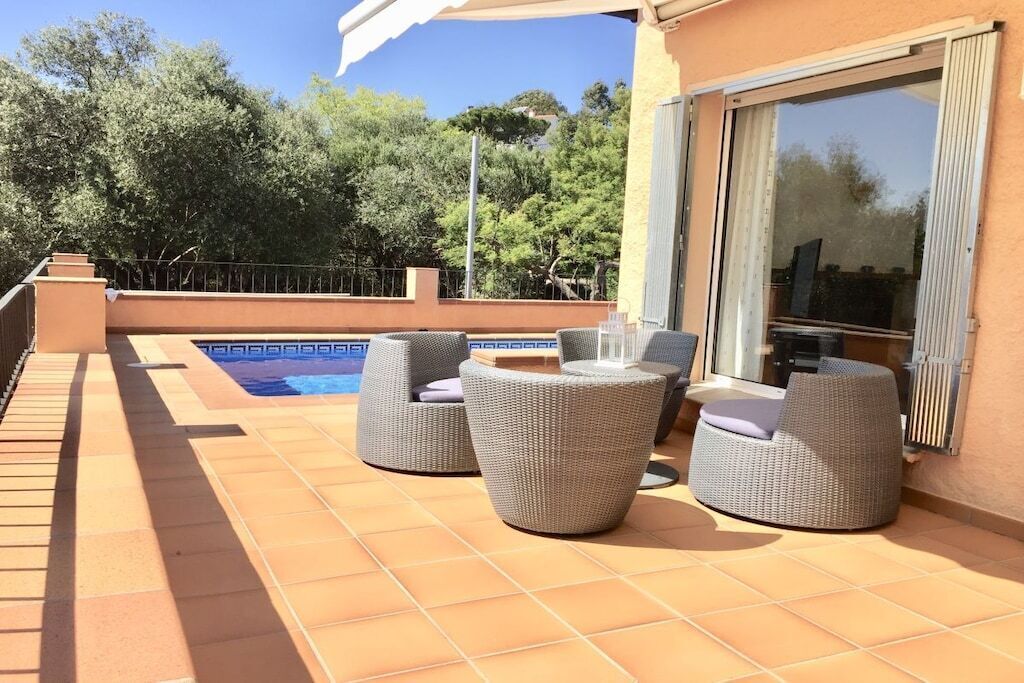 Une terrasse avec mobilier d’extérieur, une piscine et une porte vitrée donnant sur un espace abrité.