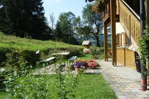 A garden with a wooden structure, a table, and chairs. - Geigelstein on the Bergerhof (Aschau im Ch. \/Sachrang)
