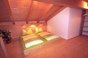A small, cozy attic bedroom with a sloped ceiling, a single bed with pillows, and a bedside table. - Geigelstein on the Bergerhof (Aschau im Ch. \/Sachrang)