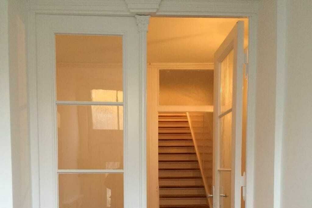 A hallway with a wooden staircase leading to an upper floor.